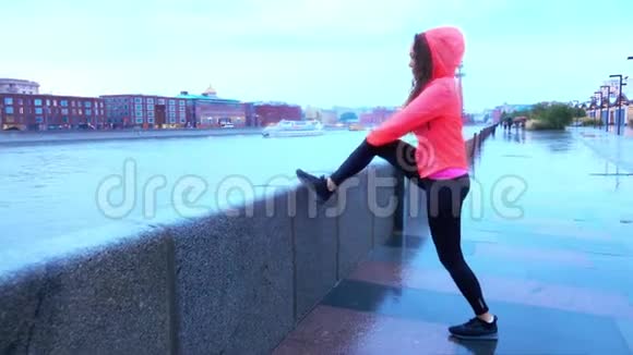 年轻的混血运动女跑步者在晚上沿着城市公园的堤岸跑步前热身视频的预览图