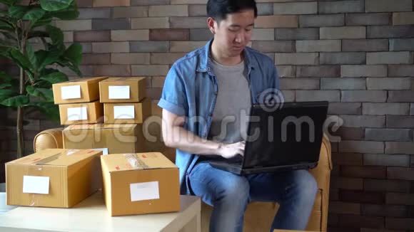 亚洲男性企业家在家使用笔记本电脑和盒装视频的预览图