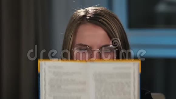 那个女学生在镜头周围的傻瓜在一本书的封面下描绘了情感愤怒惊喜快乐视频的预览图