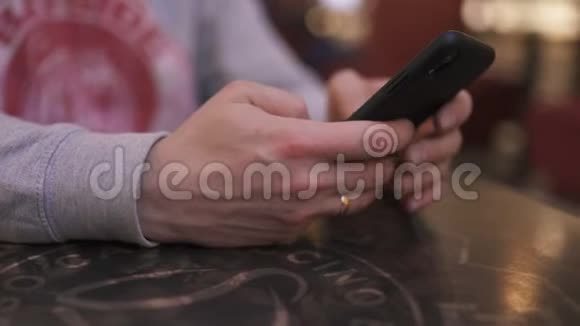 一位年轻的商人坐在咖啡馆的桌子旁用iphone和短信打字成功人士每天视频的预览图