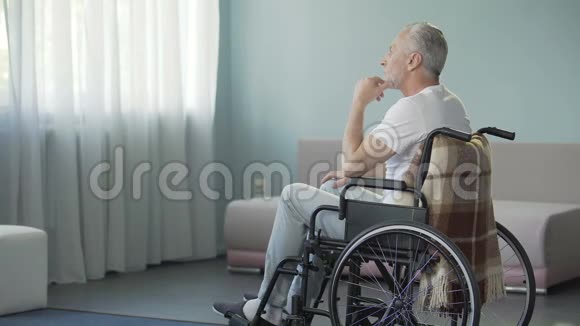 可怜的孤独老人坐在轮椅上的养老院里视频的预览图