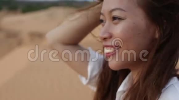 亚洲女人微笑户外沙漠风吹头发视频的预览图