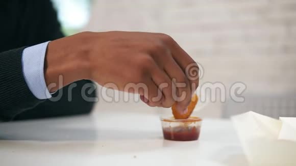年轻的非裔美国人在工作中慢镜头地把鸡块蘸上酱汁在镜头下吃视频的预览图