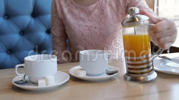 年轻女子在咖啡馆里用杯子倒水果茶视频的预览图