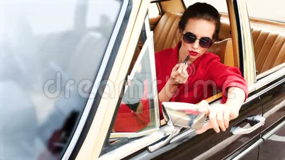戴着黑色太阳镜的漂亮女人坐在复古车里化妆视频的预览图