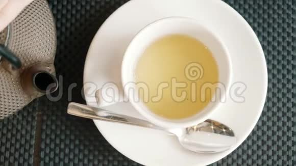 女人手把茶倒进一个白色的陶罐里特写的俯视图喝茶视频的预览图