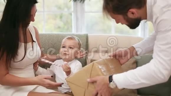 金发可爱的幼儿收到他父亲的圣诞礼物但他让他妈妈牵着他的手家庭视频的预览图