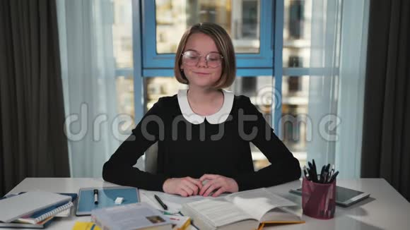 一个快乐的女学生从桌子上拿着这本书开始读做作业对着镜头微笑视频的预览图