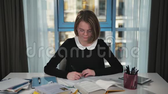 一个快乐的女学生正在考虑家庭作业找到一个主意写在笔记本上视频的预览图