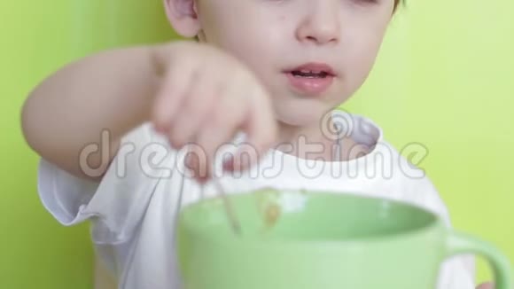 孩子自己用盘子里的勺子吃食物坐在桌子旁特写视频的预览图