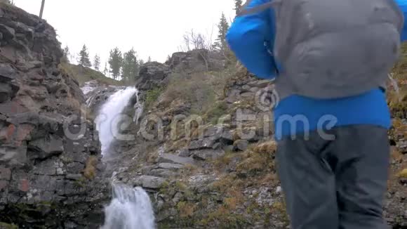 一个人带着背包沿着山区路线旅行他到达了美丽的瀑布看了看继续前进积极主动视频的预览图