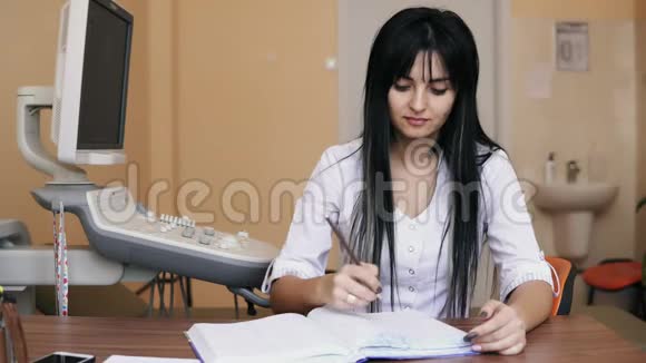 年轻女医生坐在办公桌前在诊所开处方填写表格填写健康视频的预览图