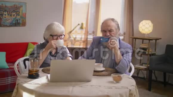 退休夫妇一起在笔记本电脑上做网上购物视频的预览图
