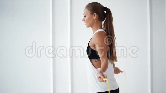 手上拿着健身追踪器的年轻女子正在体育俱乐部跳绳视频的预览图