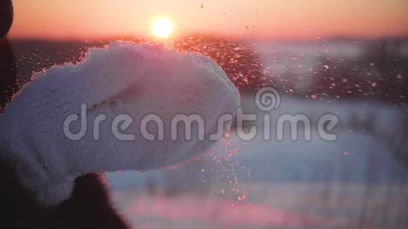 那个女孩在日落的背景下把手掌上的雪扔出去视频的预览图