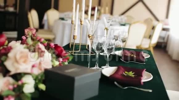 节日婚礼餐桌设置绿色鲜花餐巾纸眼镜和烛台桌子装饰特写视频的预览图
