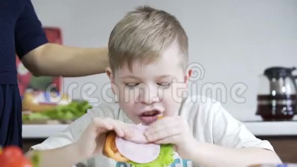 儿子在厨房吃三明治妈妈为儿子准备三明治家庭幸福视频的预览图