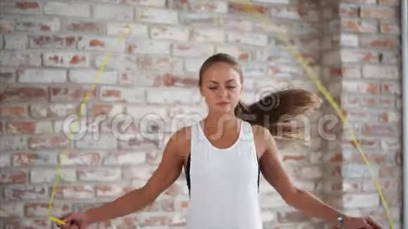 年轻的运动女孩在砖墙的背景下跳绳视频的预览图