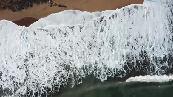 鸟瞰大型绿松石波撞击在海滨和人们在沙滩上行走库存美丽美丽视频的预览图