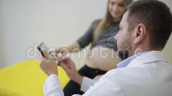 一位医生给一位孕妇看了她婴儿的超声波快照医生和孕妇在看数字视频的预览图