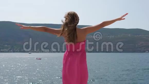 一个穿着衣服的女人把手臂伸向海边朝太阳走来视频的预览图