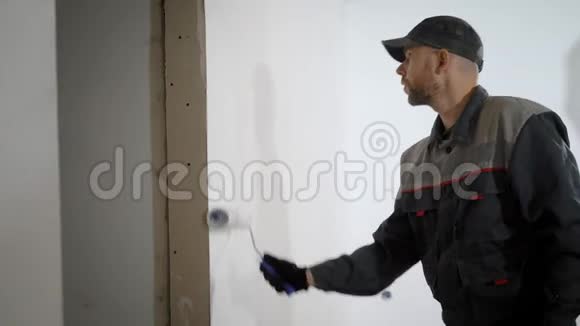 职业男子在公寓里粉刷墙壁建筑工人手里拿着一个滚筒视频的预览图