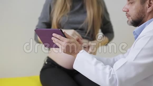 一位医生给一位孕妇看了她婴儿的超声波快照医生和孕妇在看数字视频的预览图