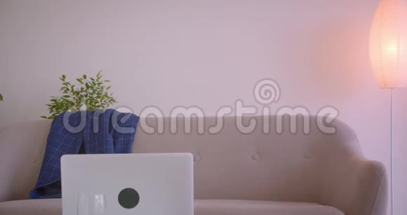 成人白种人商人在笔记本电脑上打字悠闲地坐在办公室室内的沙发上的特写照片视频的预览图