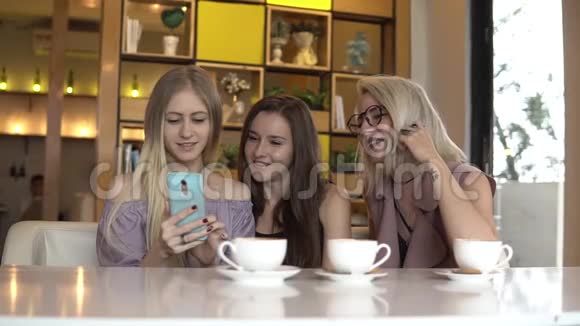 女人的友谊女朋友在喝咖啡休息时看智能手机照片视频的预览图