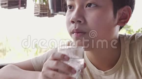 慢动作亚洲男孩早餐后从杯子里喝水用杯子把小男孩关上视频的预览图