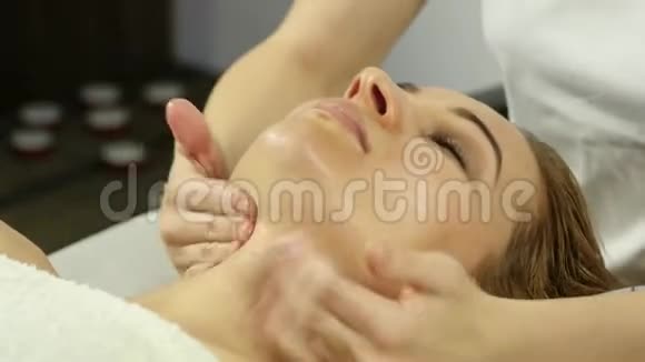 美丽的女人在水疗中心做面部按摩美容院面部皮肤护理4K视频的预览图