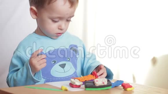 孩子在家里坐在桌旁用橡皮泥雕刻图形视频的预览图