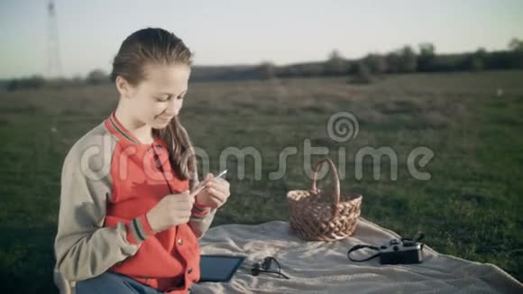 一个十几岁的女孩拿着笔在野餐时躺在毯子上写日记视频的预览图