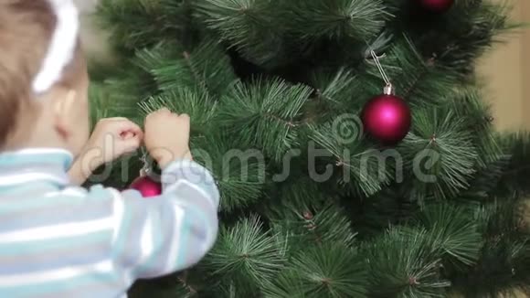 一个孩子用红色的球穿圣诞树视频的预览图