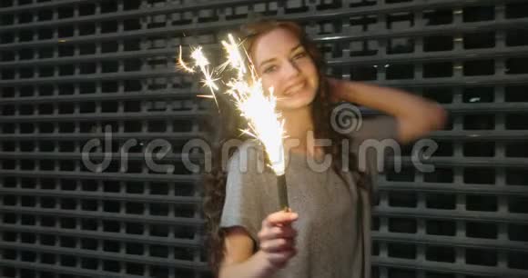 在金属栅栏前少女手中拿着火花的慢镜头视频的预览图