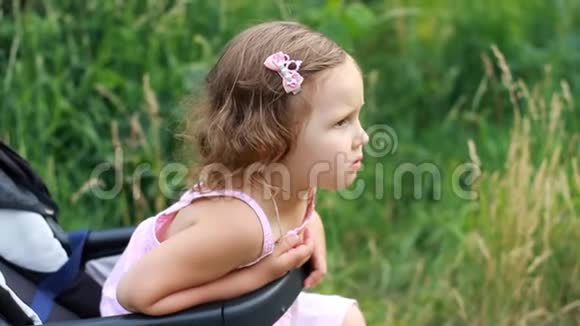 悲伤的孩子坐在婴儿车里等待她的母亲不满和冒犯孩子视频的预览图