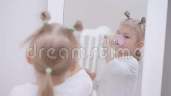 镜子前的一个小女孩用刷子在她的脸上化妆一个可爱的小女孩的肖像视频的预览图