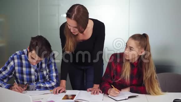 三个正在做作业的学生坐在桌子旁一个女孩在听写另外两个在做作业视频的预览图