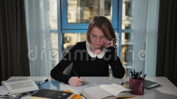 一个疲惫心烦意乱的女学生自拍在笔记本上罢工愤怒地扔了支笔她做家庭作业视频的预览图
