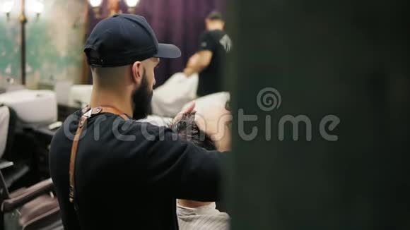 留胡子的时尚理发师的侧和后视手里拿着剪发刷剪发视频的预览图