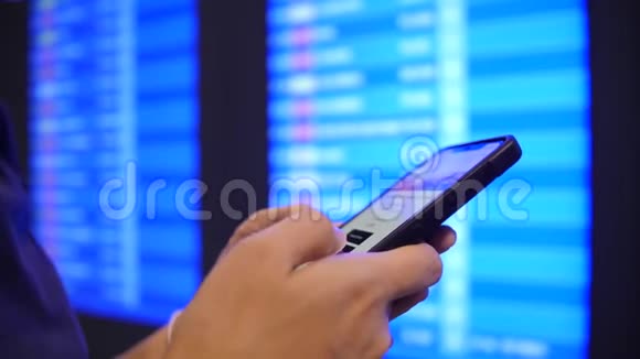旅游妇女使用手机在机场离港板附近检查她的航班时间4K慢动作泰国曼谷视频的预览图