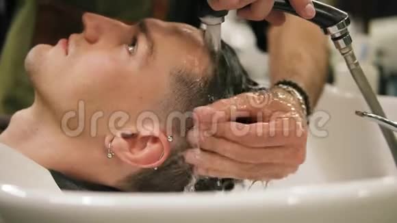 一位年轻时尚男士的侧视他的耳朵被一个理发师洗了头发视频的预览图