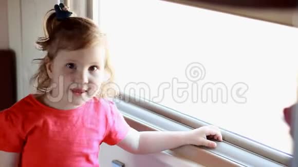 小女孩乘火车旅行婴儿乘火车旅行看着窗外视频的预览图