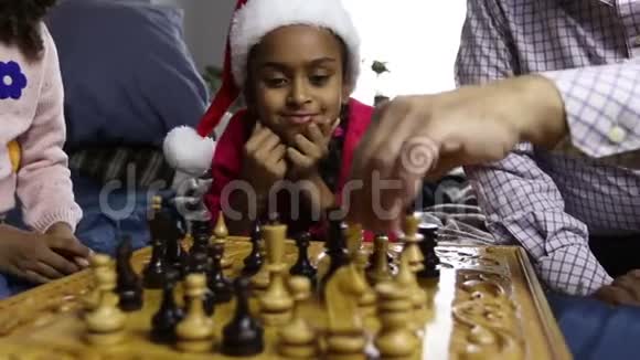 戴着圣诞帽的微笑女孩在看象棋比赛视频的预览图
