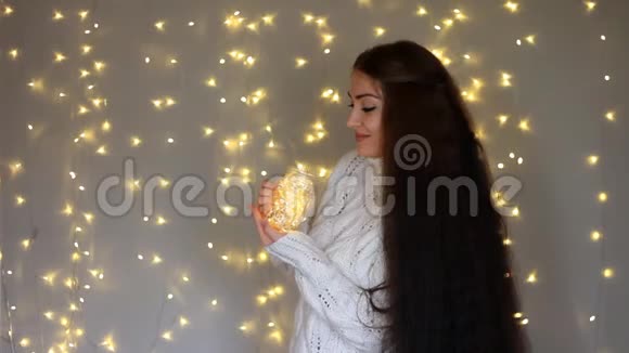 美丽的女人穿着温暖的白色毛衣手里拿着一盏灯闭上眼睛做梦视频的预览图