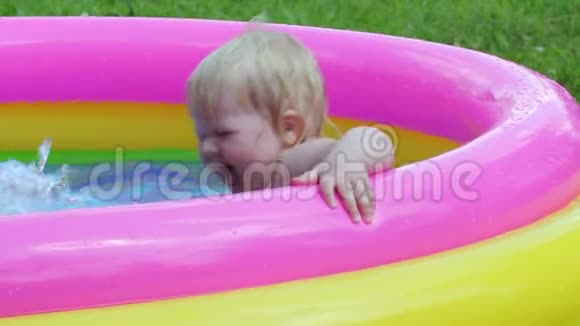 夏季娱乐活动女婴在院子里的充气游泳池里洗澡视频的预览图