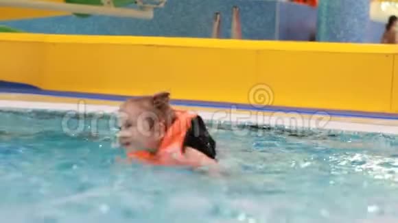穿着救生衣在游泳池里的小女孩学会游泳在水里游泳的婴儿视频的预览图