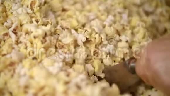 工人在爆米花机上用勺子搅拌爆米花准备电影的食物视频的预览图