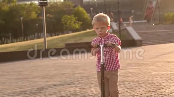 日落时分在城市公园骑摩托车的小男孩视频的预览图