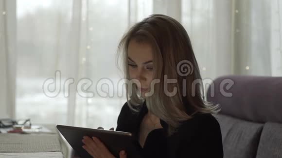 微笑的女人看着屏幕平板电脑坐在咖啡馆的桌子上视频的预览图
